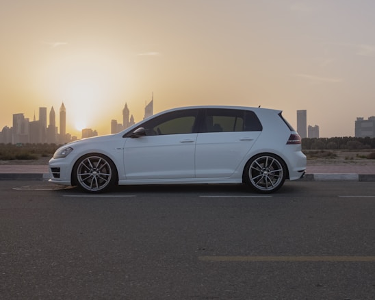 A clean, well-maintained rental car parked in front of a city skyline at sunset.