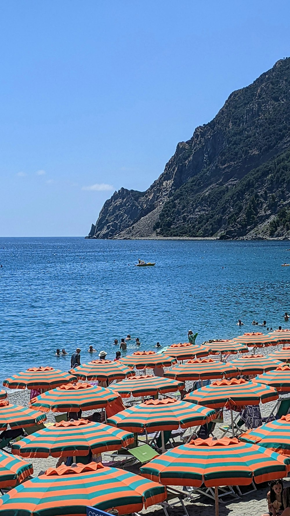 a beach with many umbrellas and a large mountain in the background