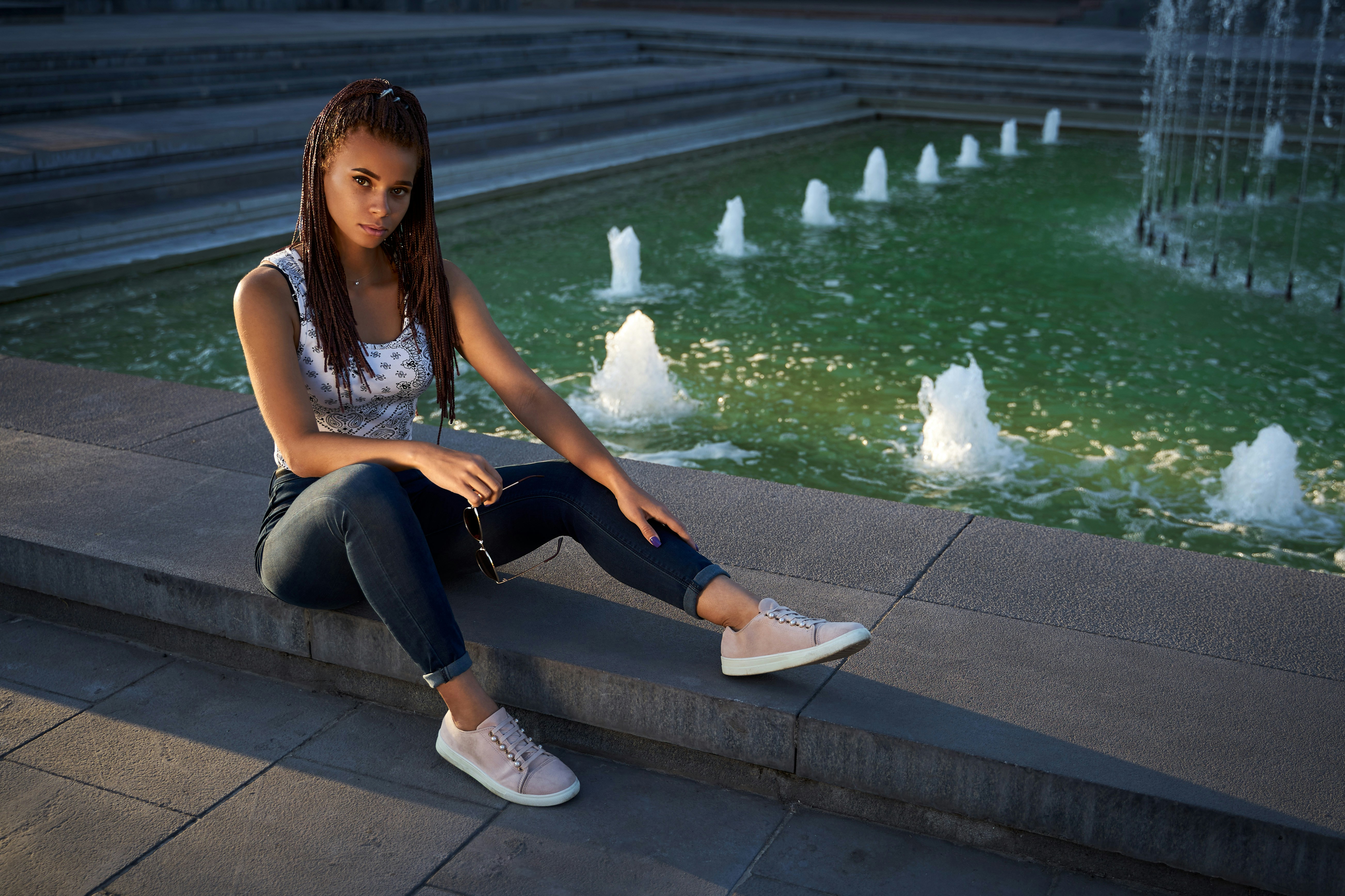 a woman sitting on a ledge next to a pool