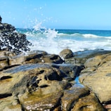 Waves crashing against a sturdy breakwater under a clear sky.