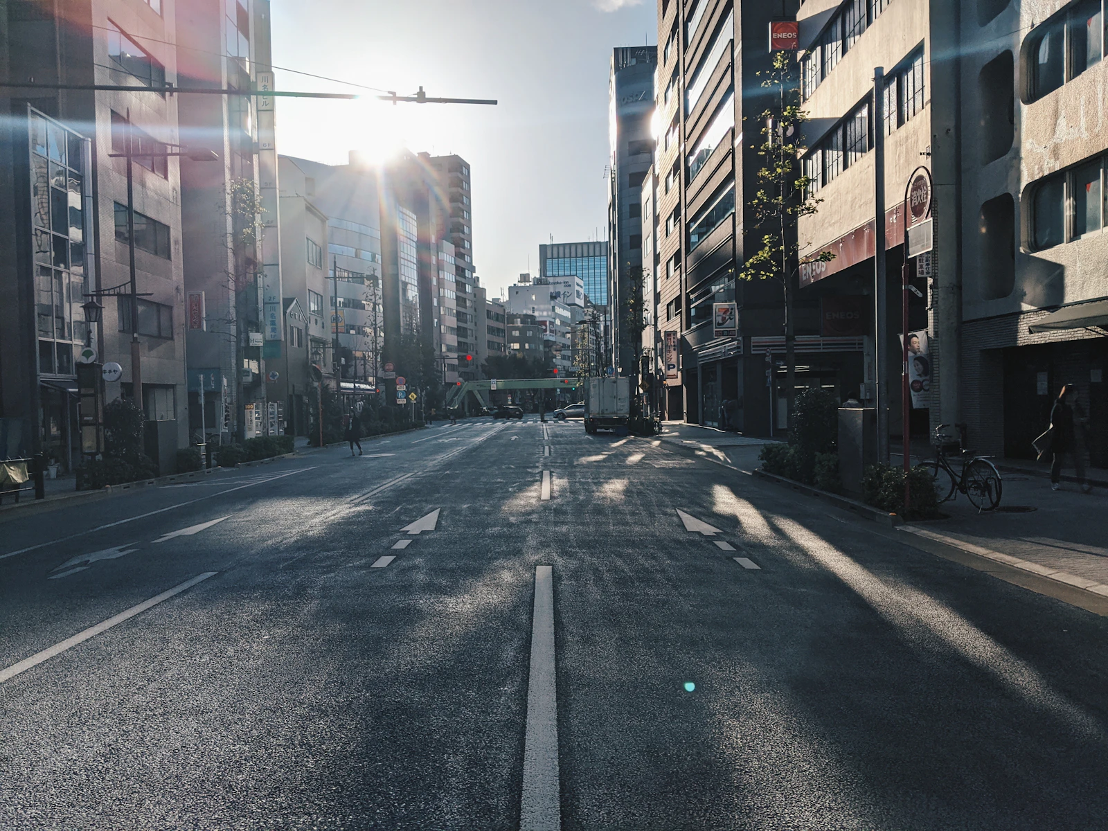 Warm sunlight reaches a quiet urban street between closely set buildings.