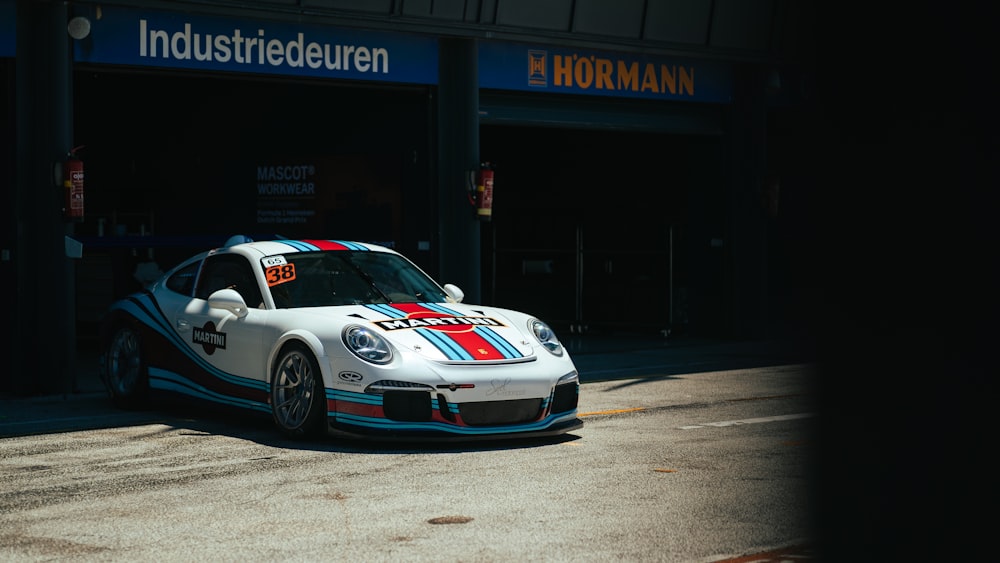 um carro de corrida branco estacionado em frente a um posto de gasolina