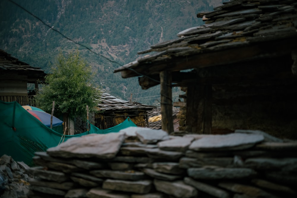 a stone building with a tree and mountains in the background