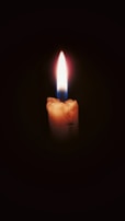 A candle burning brightly in a dark room, symbolizing faith in darkness.