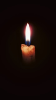 A candle burning brightly in a dark room, symbolizing faith in darkness.