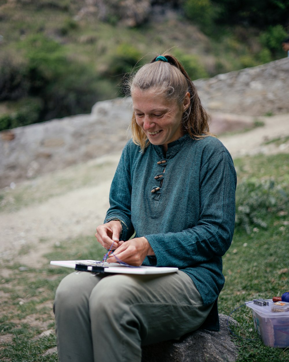 a person sitting on a rock writing on a piece of paper