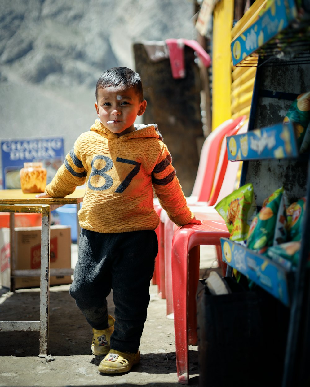 a boy standing next to a red chair