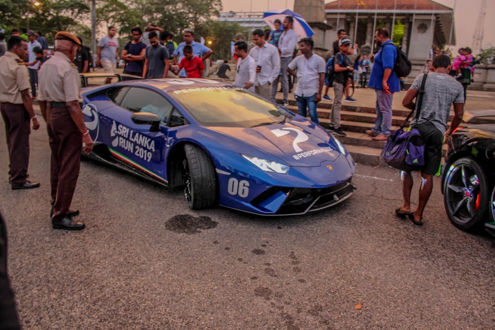 a blue car parked in a lot with people around