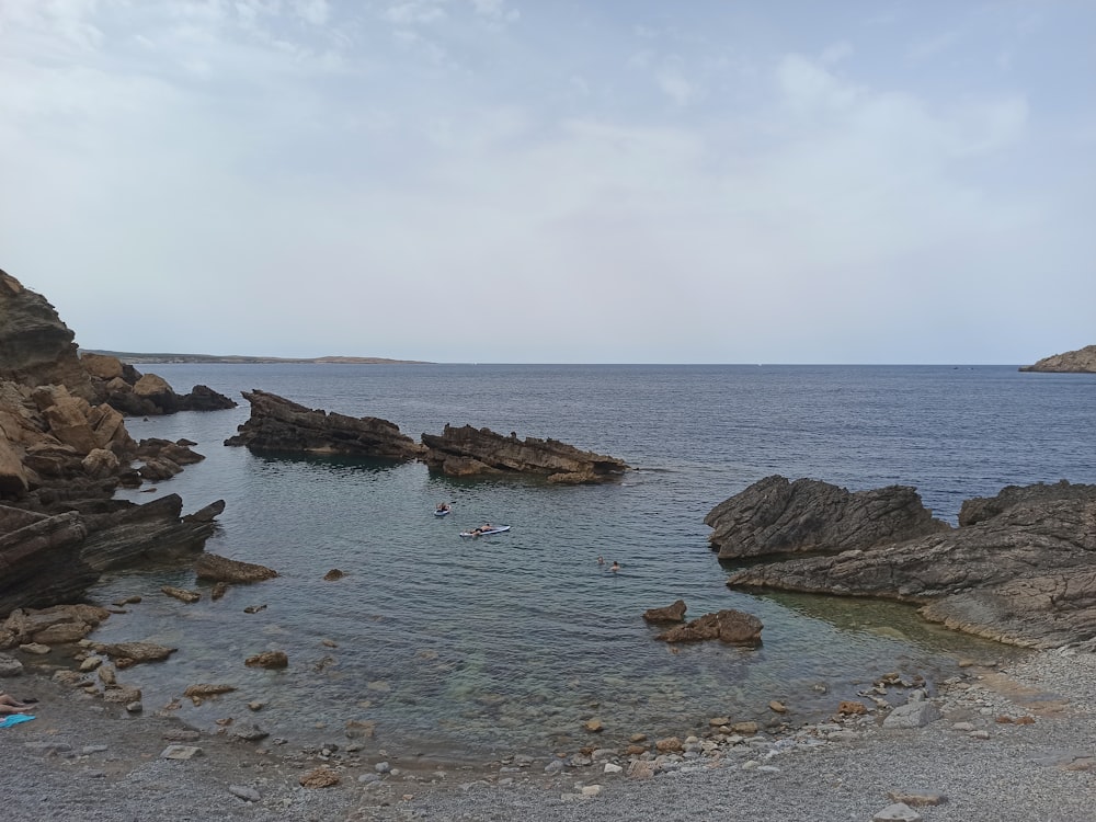 uma praia rochosa com um corpo de água no fundo