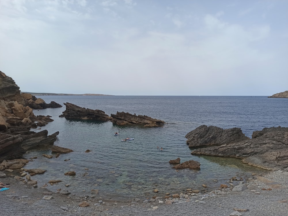 a rocky beach with a body of water in the background