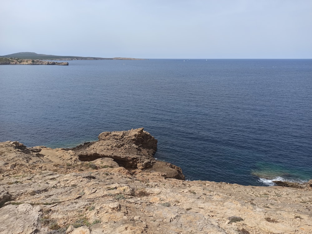 a rocky beach with a body of water in the background