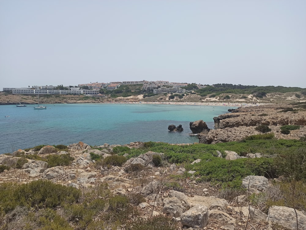 Una playa rocosa con una ciudad al fondo