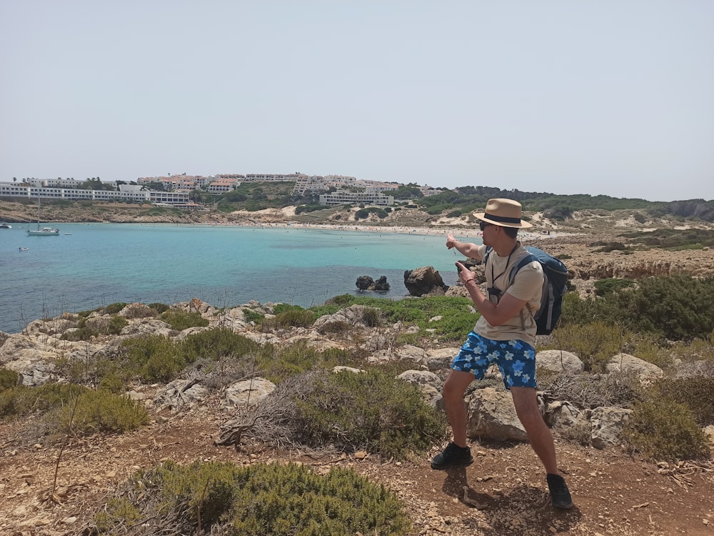 a man standing on a hill looking at a body of water