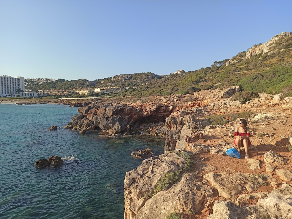 une personne assise sur un rocher au bord de l’eau