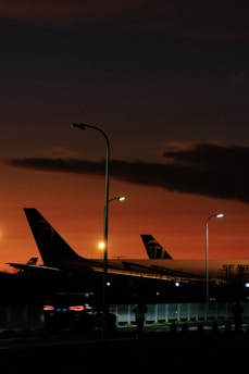 A sleek commercial airplane parked on the runway during sunset