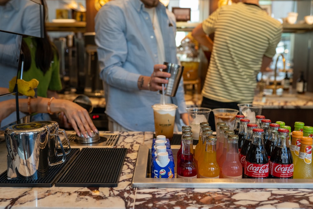 um grupo de pessoas em pé ao redor de um bar com bebidas
