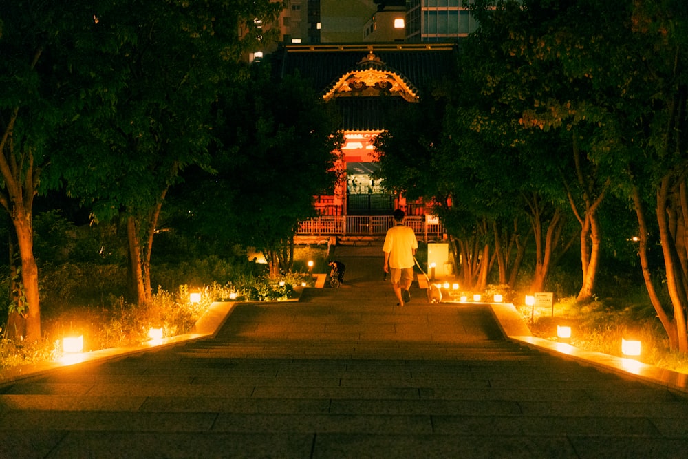 a person walking down a sidewalk with a group of lit candles