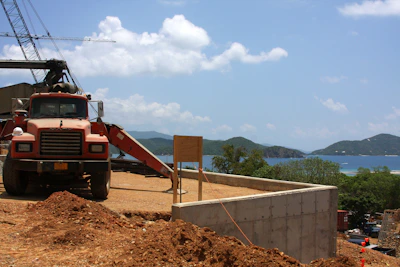 A sturdy dumpster parked at a busy construction site with mountains in the background under a clear blue sky.