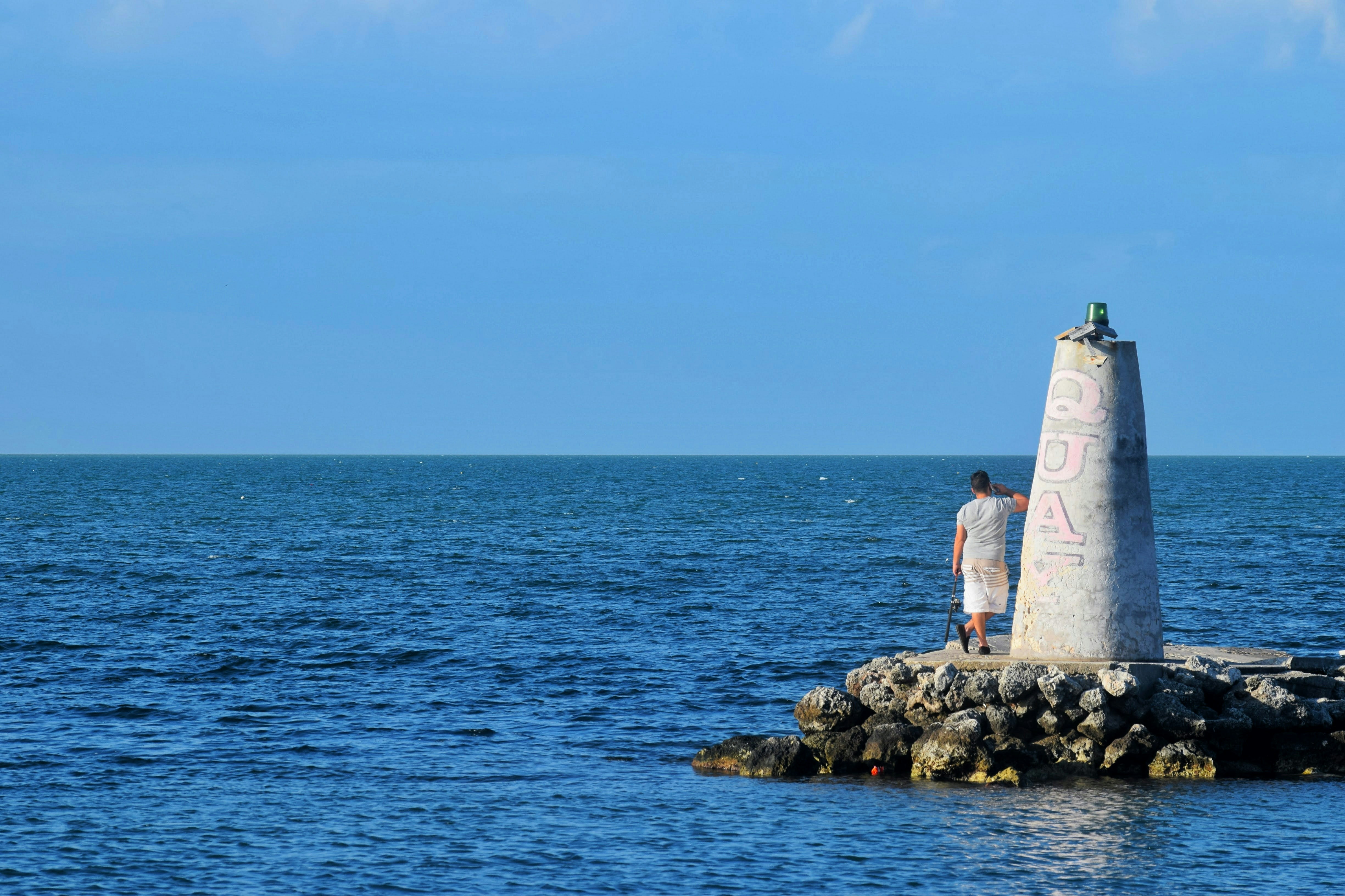 a man standing on a rock in the water, A lot of blue in one pic. Shot on the way to Key West. It was an amazing drive. 