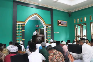 An advisor respectfully discussing health tips with mosque elders in a serene meeting room.