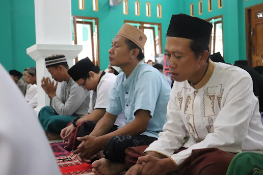 A group of men gathered in a warm, sunlit room, sharing a moment of prayer and brotherhood.