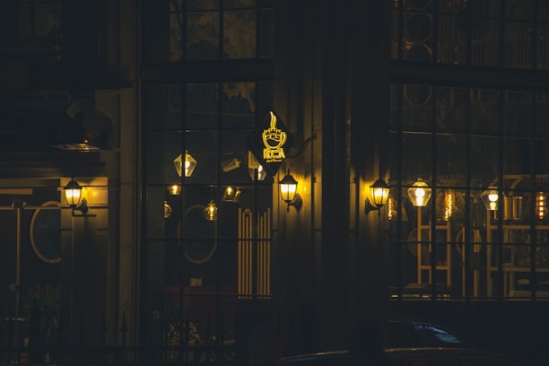 Exterior view of Abdeen Café at dusk with warm orange lights glowing against a black facade.
