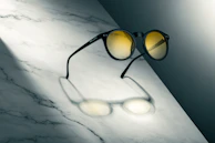 Artistic composition of black sunglasses with golden accents, emphasizing the personalized engraving on the temple.