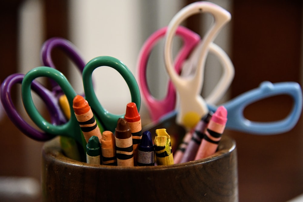 a group of scissors and pens in a cup