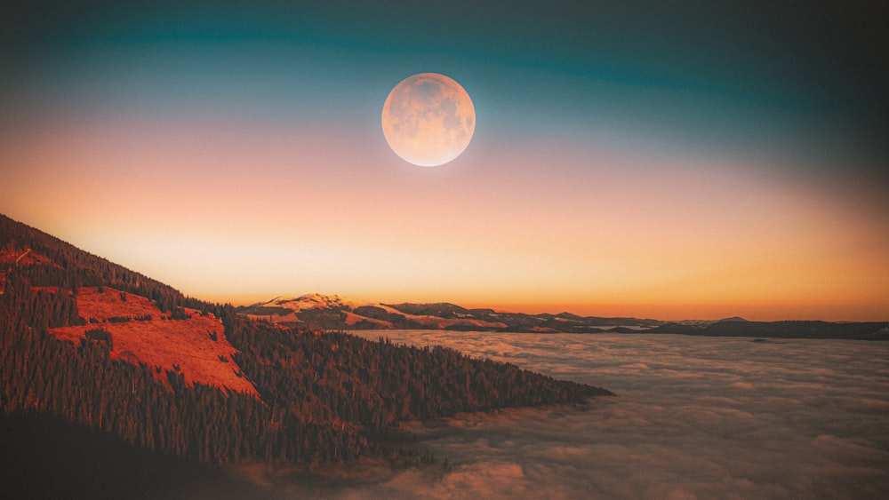 a landscape with hills and a moon in the sky