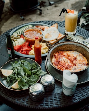 a table with plates of food and a glass of juice