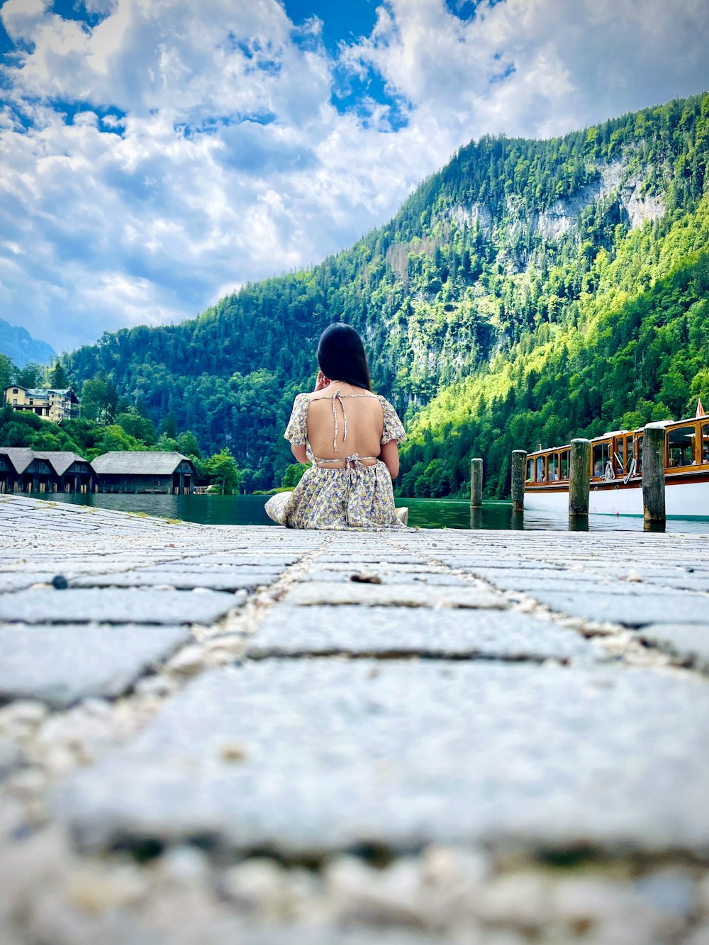 a person sitting on a rock in front of a lake and mountains