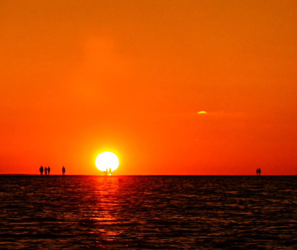 a group of people standing in the water at sunset