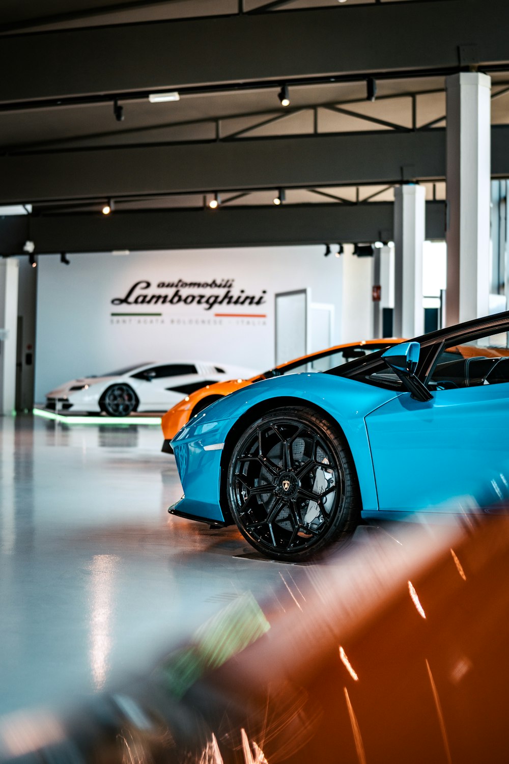 a blue sports car parked in a showroom with a white wall