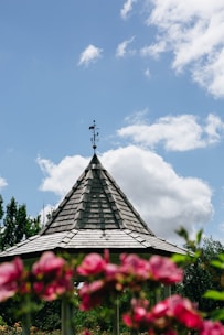 Handcrafted wooden gazebo surrounded by blooming flowers on a sunny day.