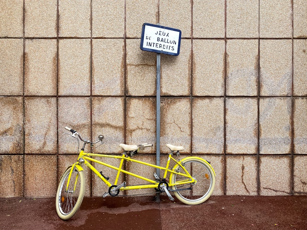 a yellow bicycle parked next to a sign