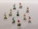 A collection of painted wooden figurines depicting soccer players mounted on small blocks, arranged in a grid-like pattern on a light-colored wall. Each figurine is in a dynamic pose, suggesting movement typical of a soccer game. The players are wearing uniforms in red, blue, and orange, and their hairstyles and expressions are distinct.