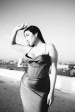 Black-and-white photo of a model striking a dynamic pose on a city rooftop at dusk.