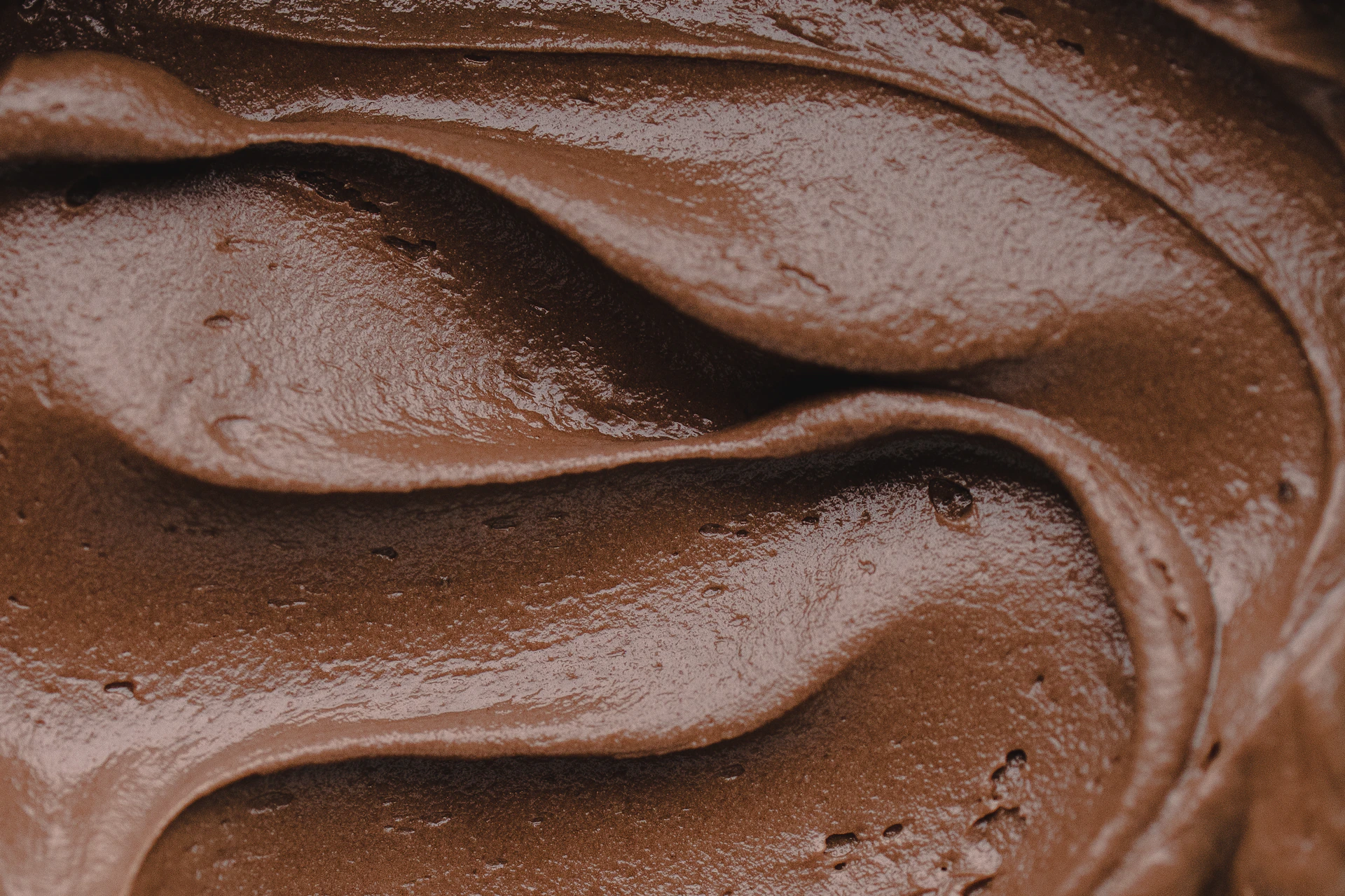Smooth swirls of dark chocolate frosting with a glossy texture