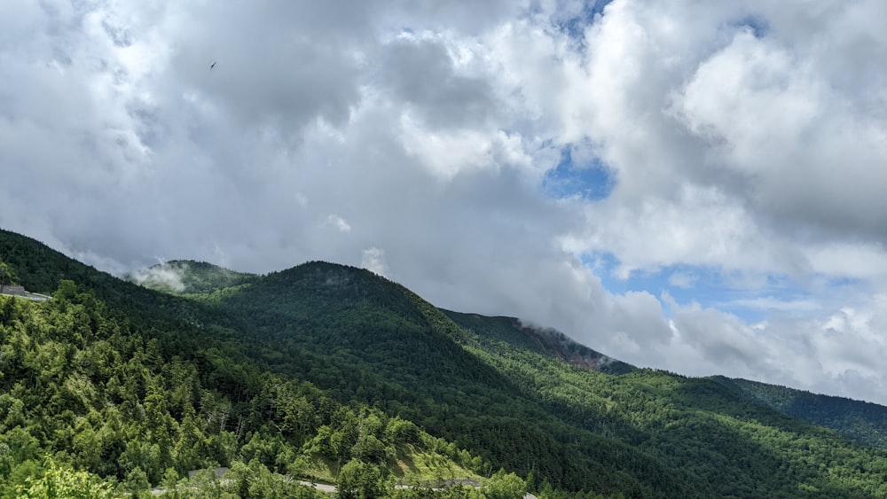 a green mountain with clouds