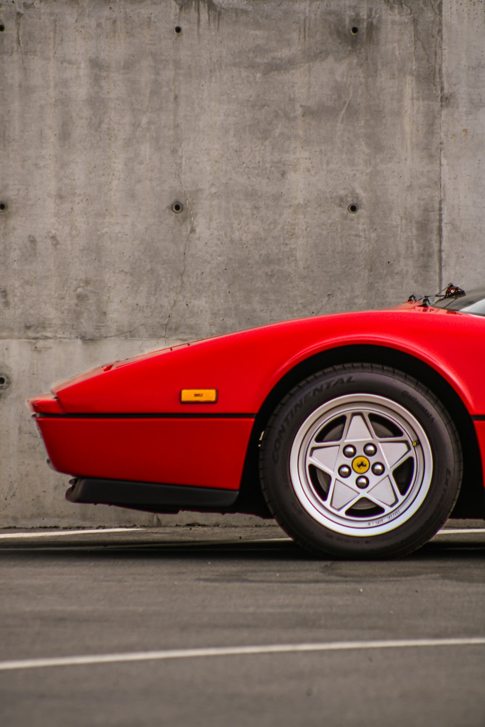 a red car parked next to a concrete wall