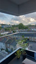 Balcony view overlooking a quiet neighborhood with greenery and blue skies.