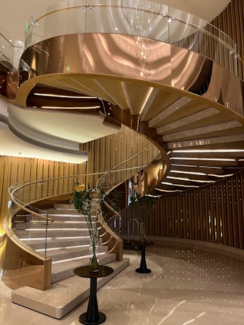 Elegant glass staircase with sleek, transparent panels and golden accents in a luxury home.