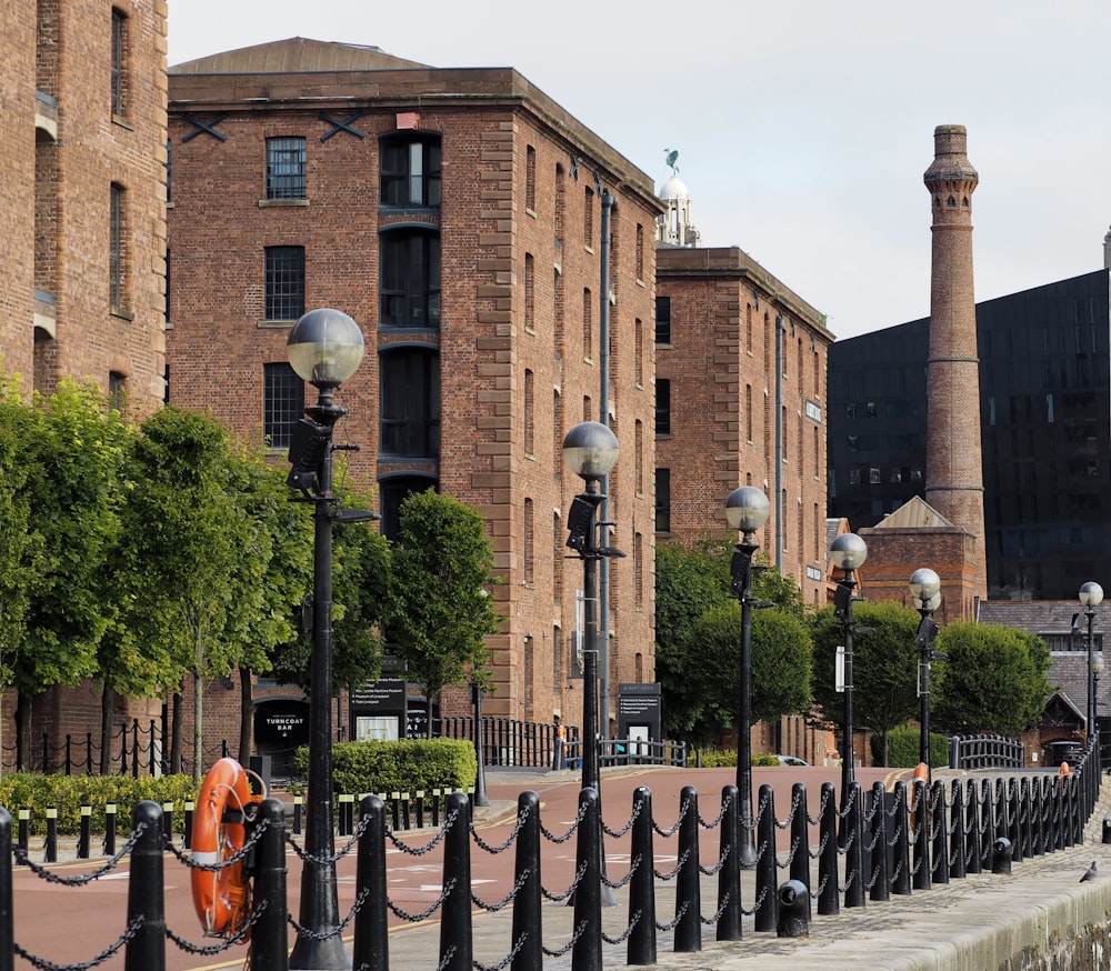 a brick building with a fence and trees in front of it