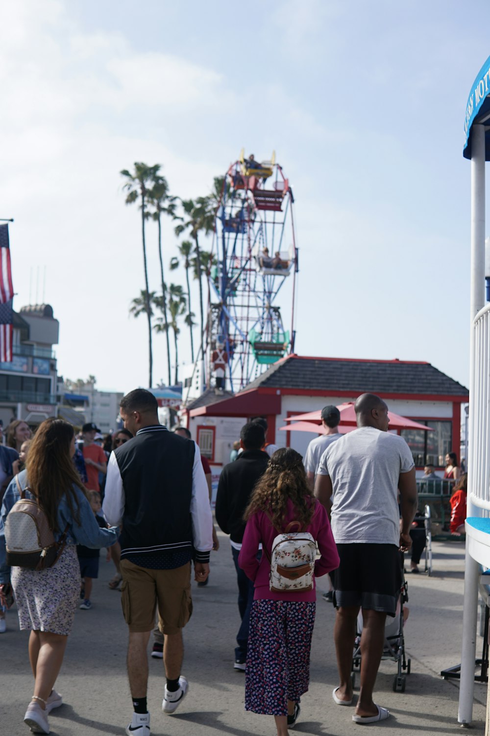 a group of people walking on a sidewalk next to a roller coaster