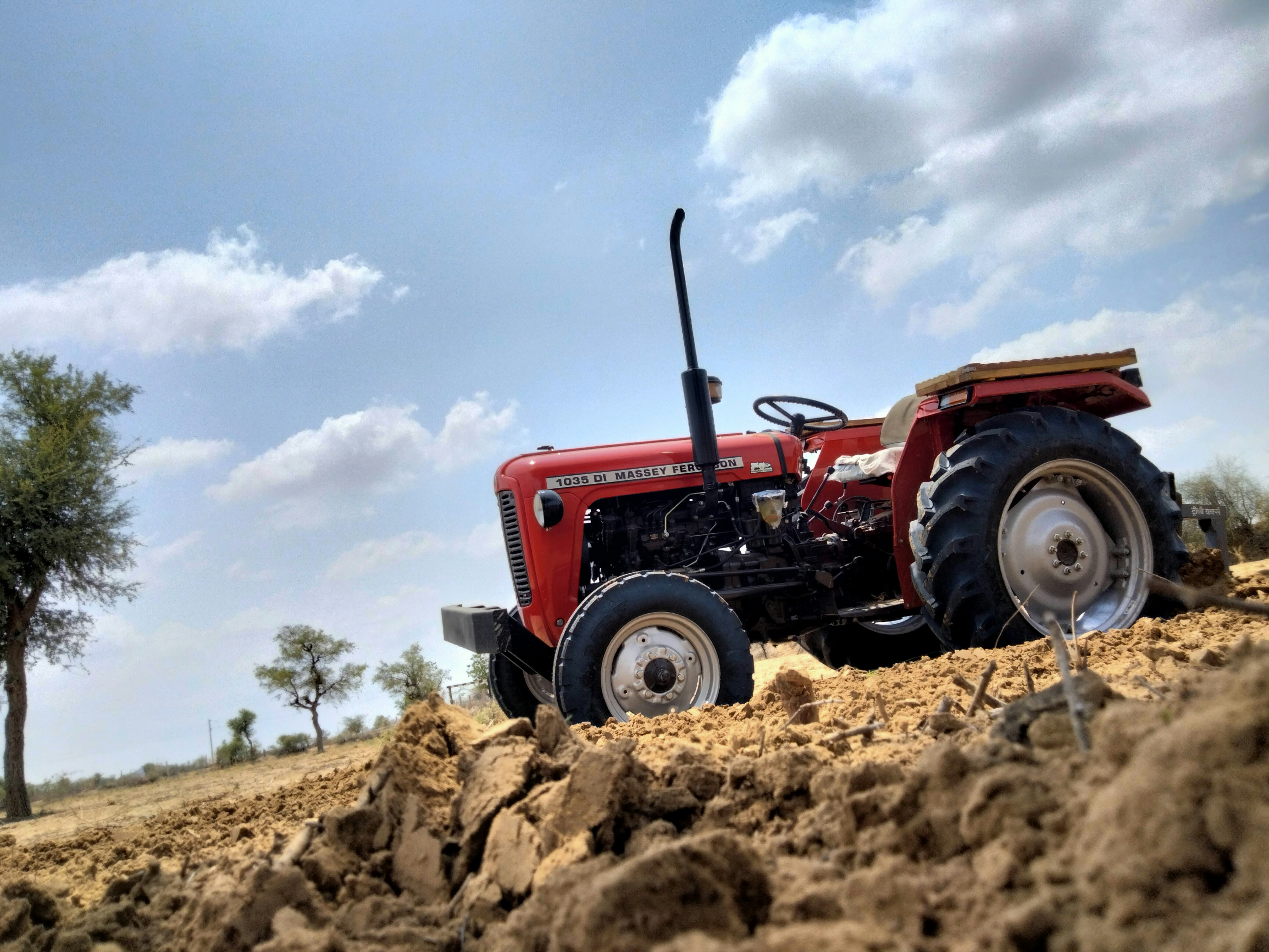 Tractor working on open farmland under bright South African sun, rich brown soil being tilled