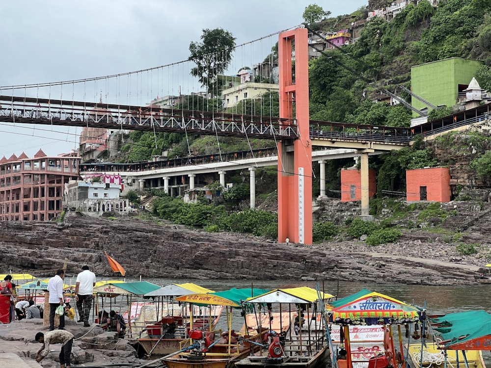 a group of people standing next to a large red bridge