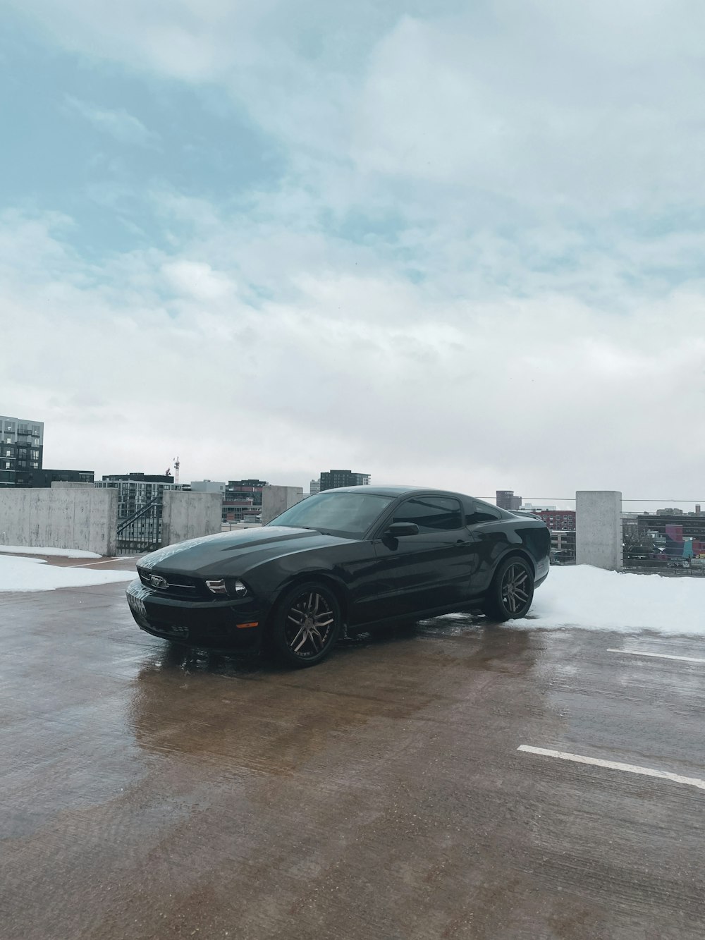 a black car parked in a parking lot with buildings in the background