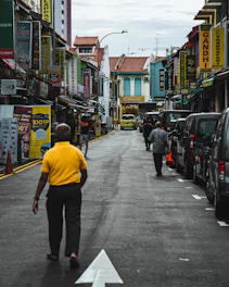 A bustling city street scene with people walking and colorful storefronts.