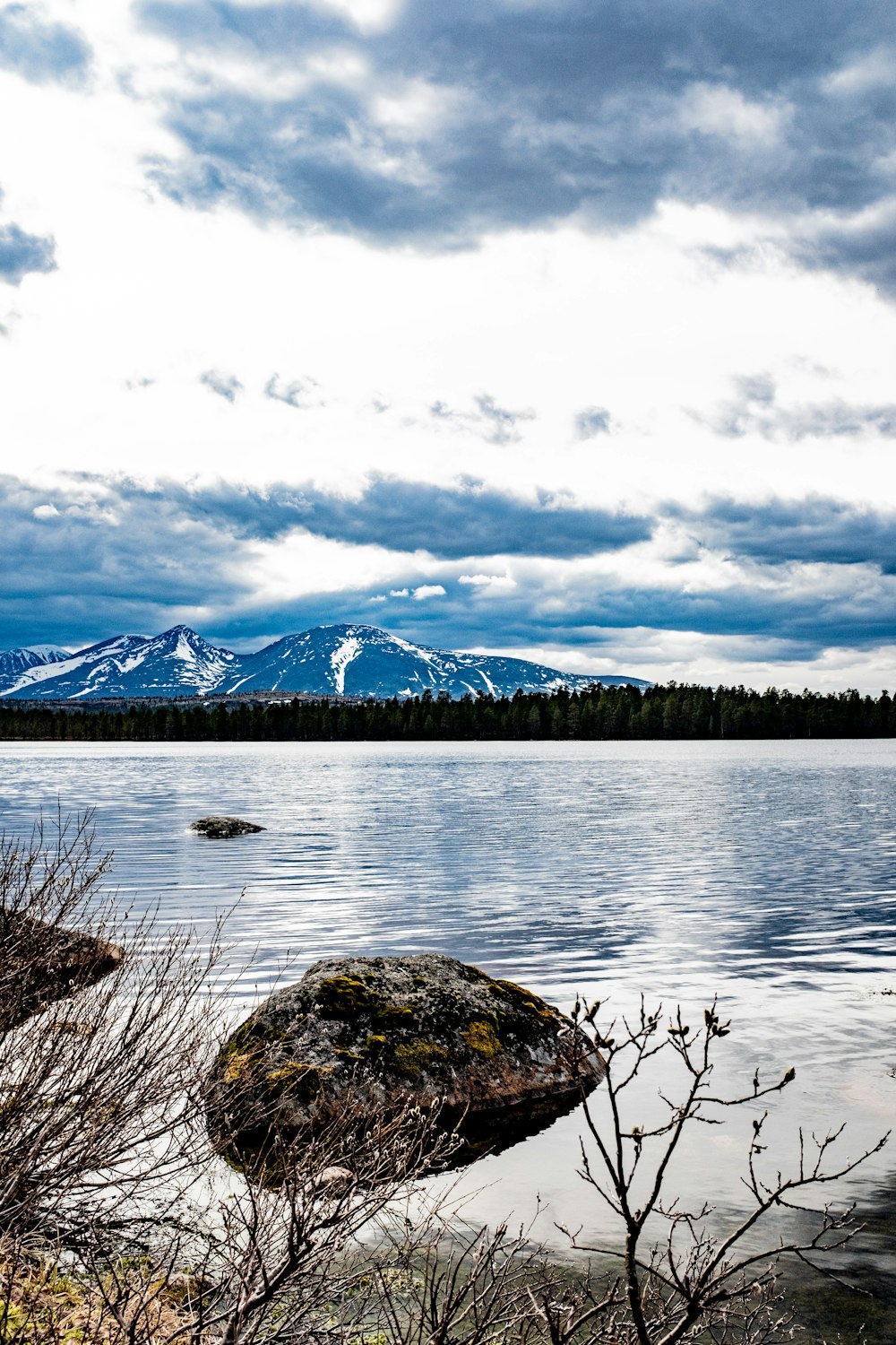 a body of water with a rock in it and mountains in the background