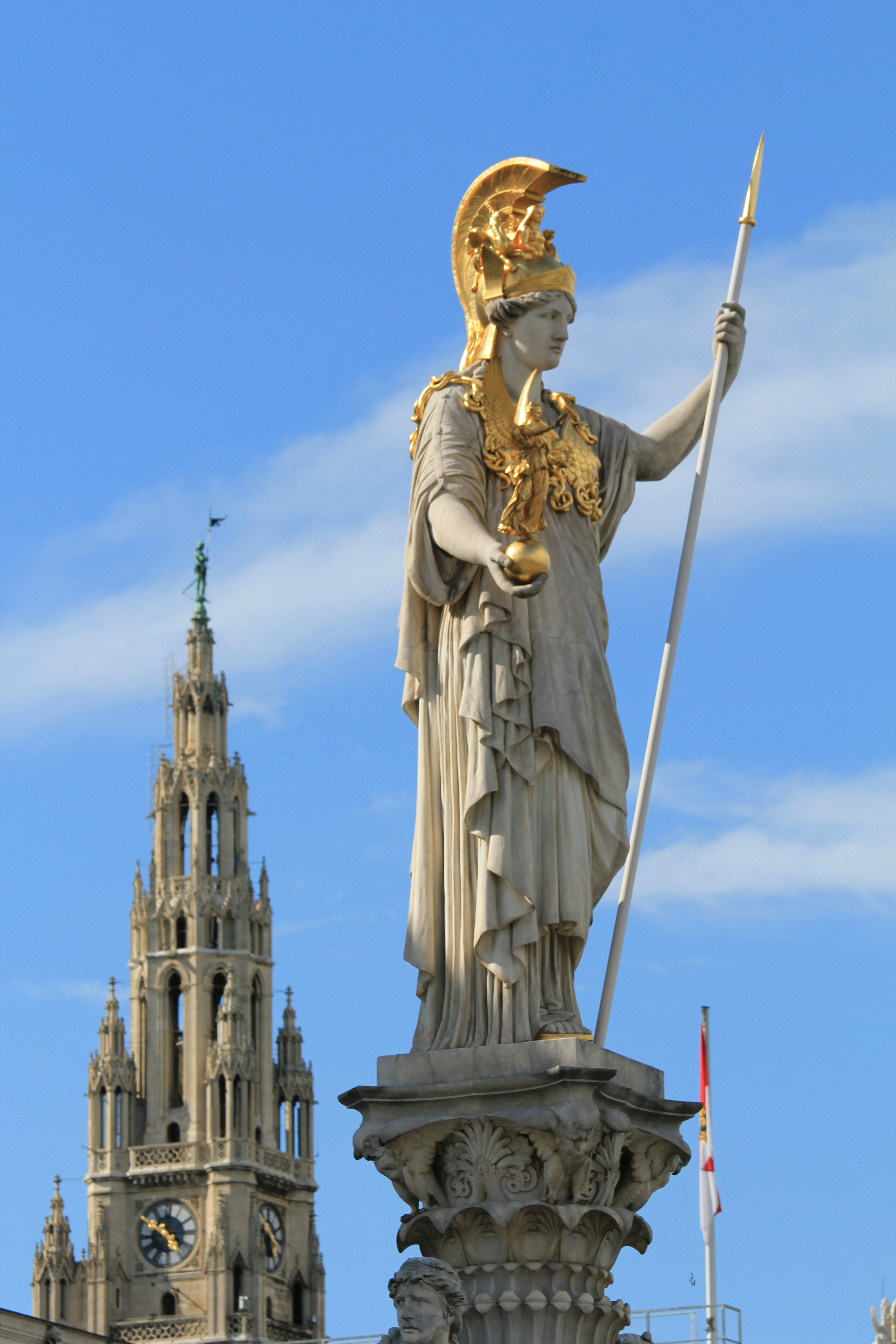 eine Statue einer Person, die einen Stab vor einem Gebäude hält